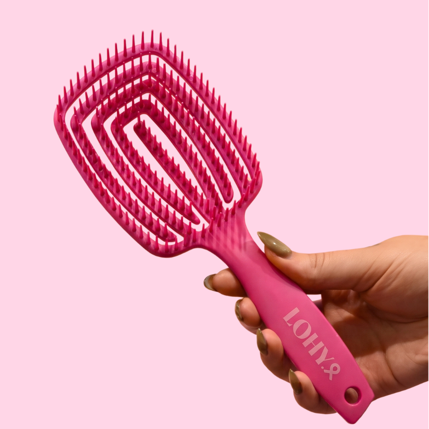 hand holding LOHY. pink paddle brush