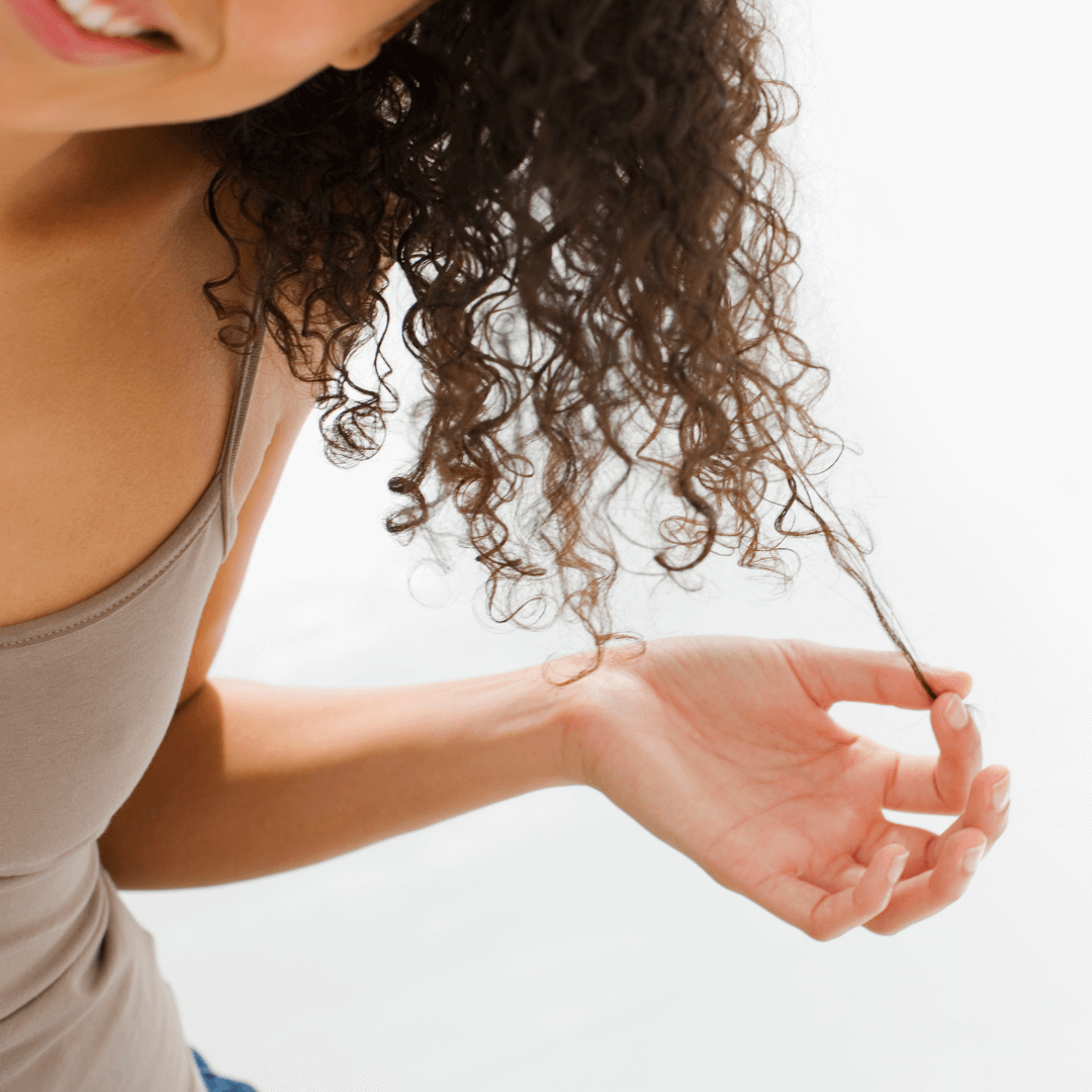 woman pulling curly hair strand brunette