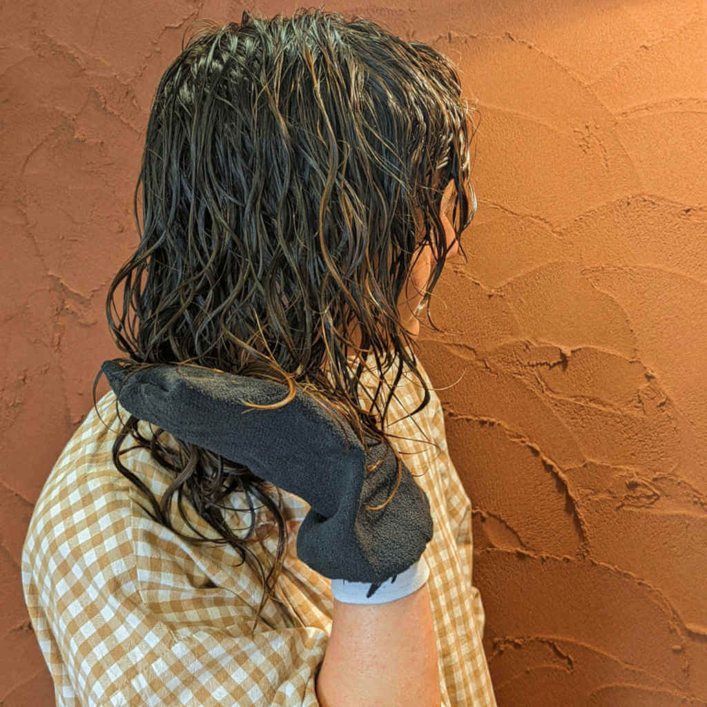 Person with wet curly hair being lifted up by the curl hydration glove